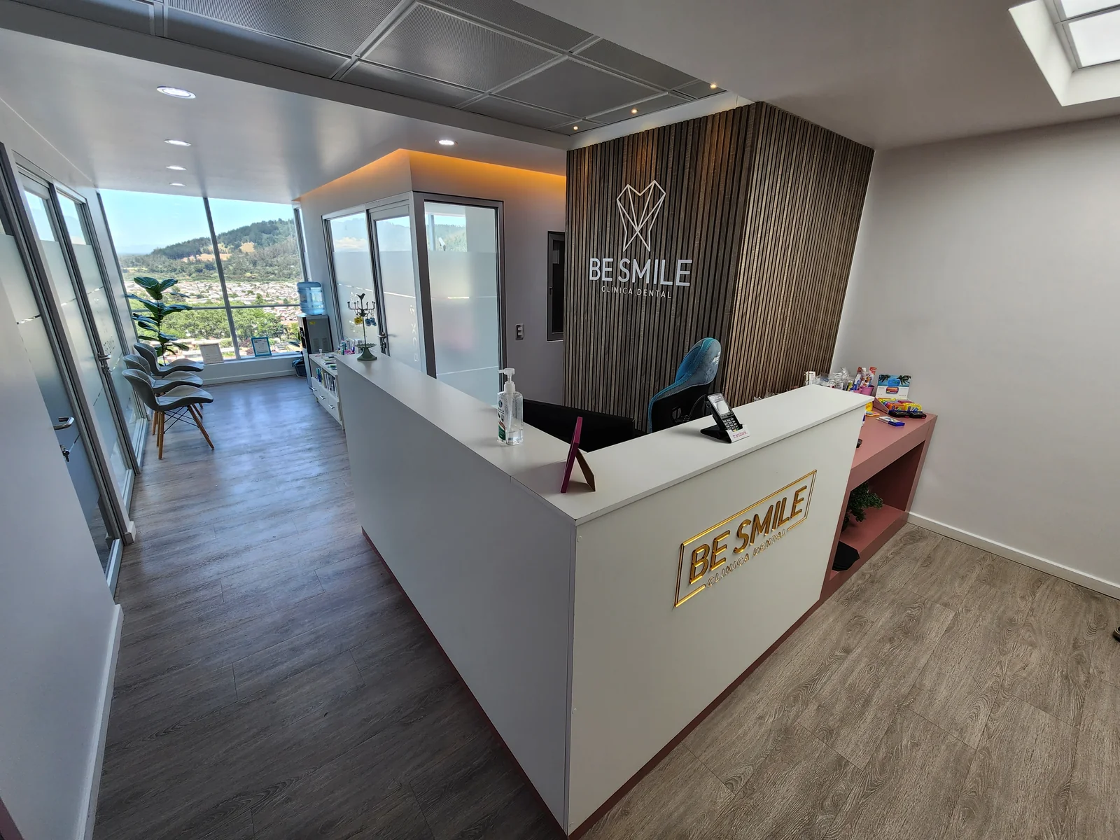 Recepción de una clínica dental entregada, con mesón blanco y muro de listones de madera