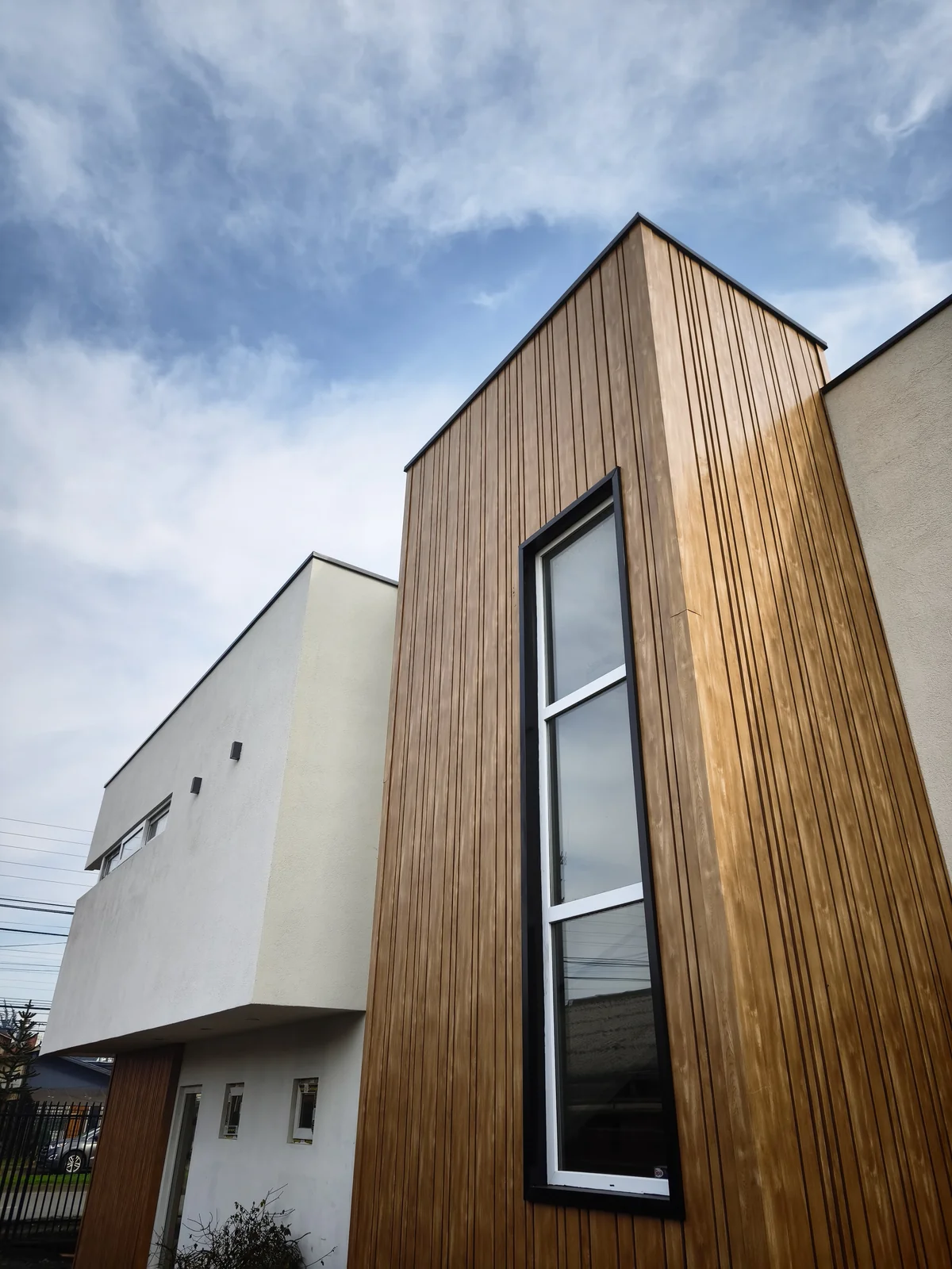 Fachada de madera con ventana vertical del Centro de Salud TOP HEALTH, en Temuco